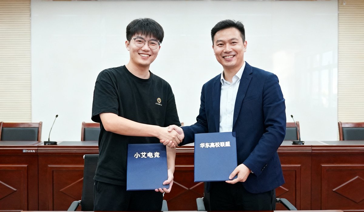 小艾电竞与华东高校电竞联盟代表握手签约的仪式照片，双方笑容满面交换合作协议文件